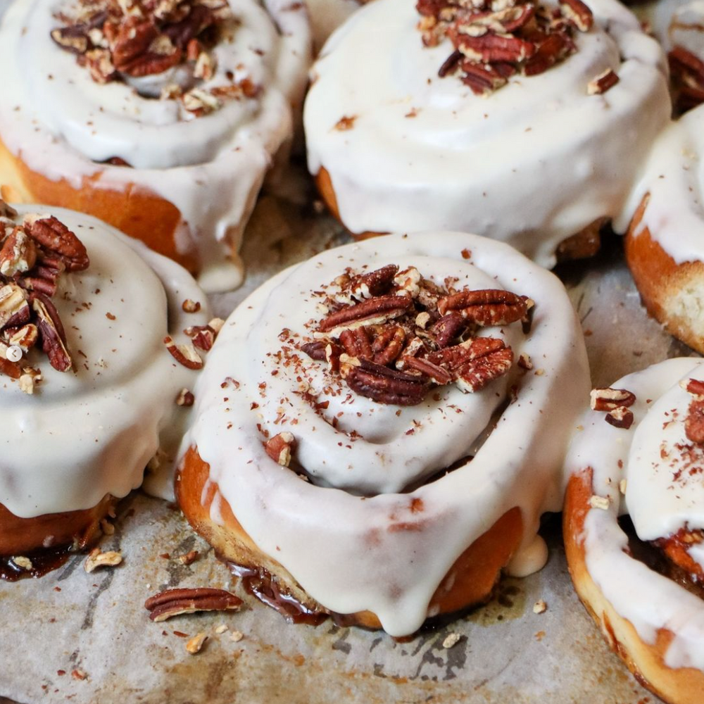 Freshly baked cinnamon rolls topped with cream cheese frosting and pecans at Comptoir Bakery, London.